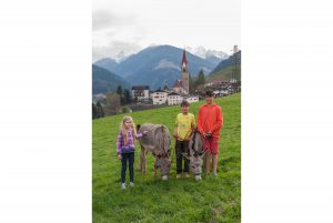 Kinder mit Esel auf der Wiese, vor St. Pankraz, Ultental